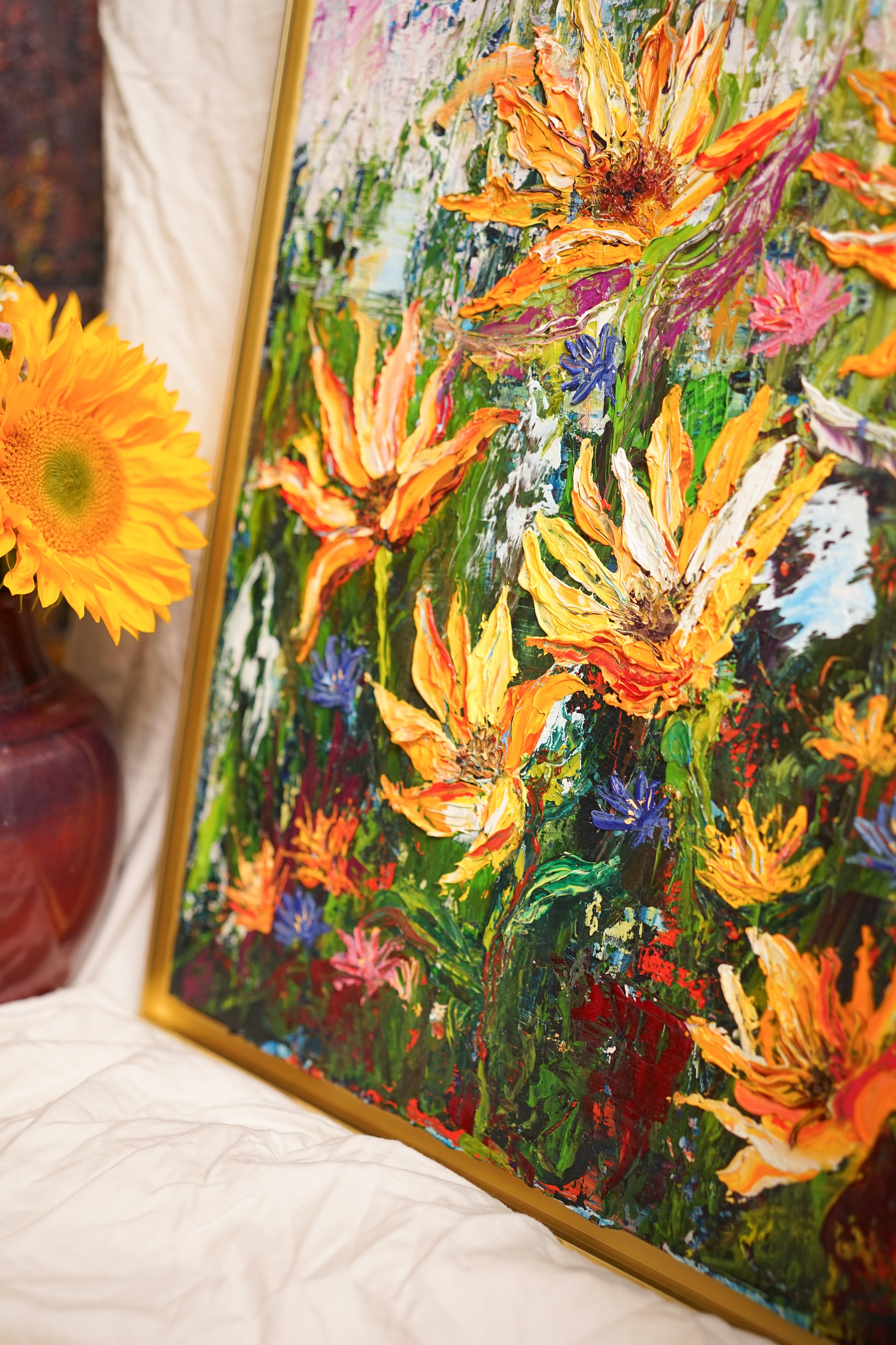 Abstract expressionism oil painting of vibrant sunflowers by artist Chelsea Tikotsky. This contemporary artwork features loose, painterly strokes with a blend of rich, bold colors, creating a romantic feel. Inspired by nature & florals, this large botanical piece offers texture, movement, & depth, perfect for home decor or art collectors seeking unique abstract art. Ideal for a living room, this statement piece brings warmth, elegance, & a refreshing botanical essence into any interior design